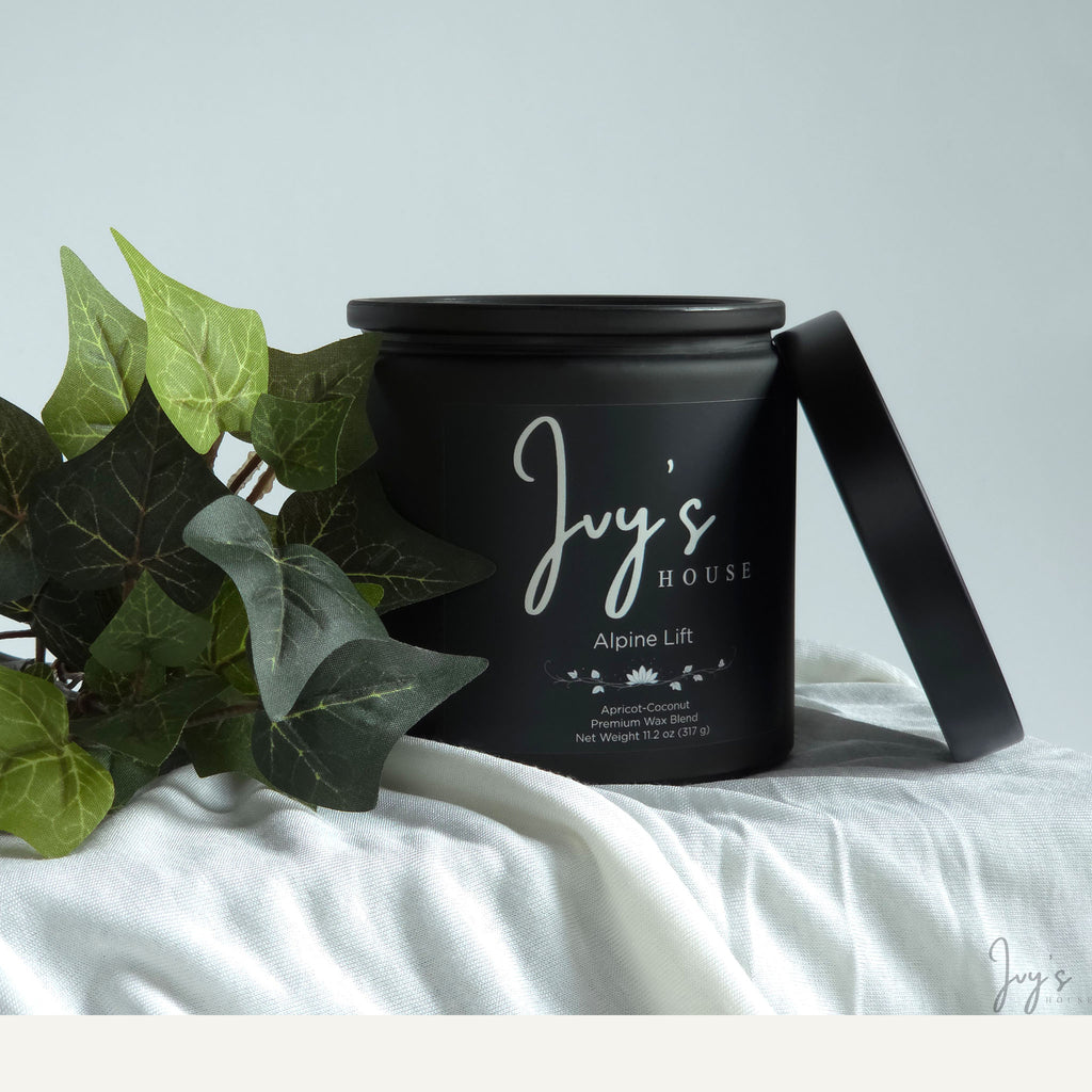 Alpine Lift premium scented candle by Ivy’s House with ivy leaves on soft white fabric