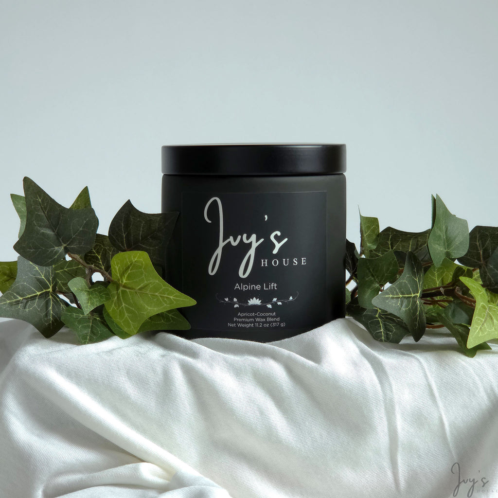 Alpine Lift premium scented candle by Ivy’s House with ivy leaves on soft white fabric