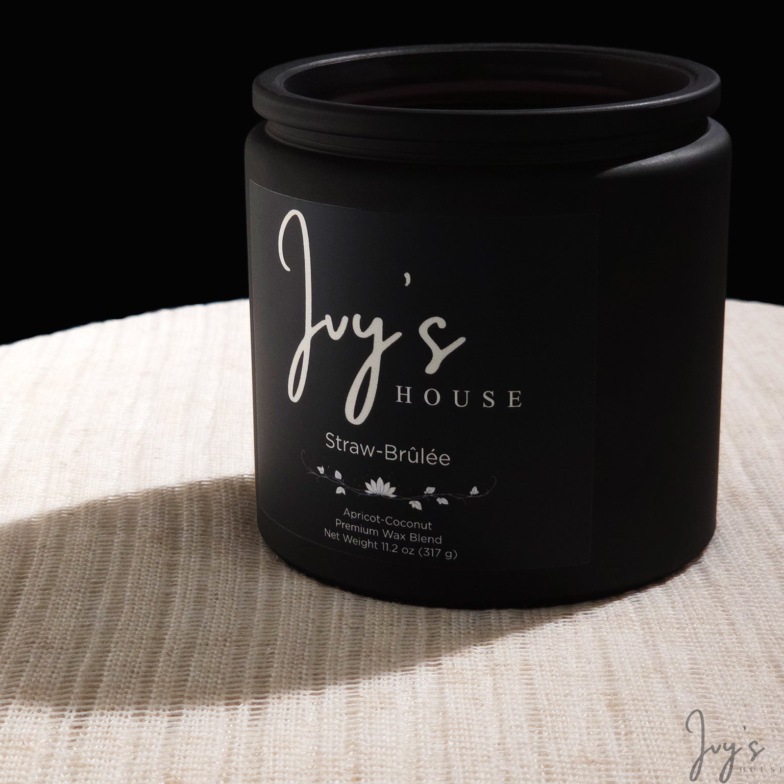 Straw-Brûlée candle by Ivy’s House on textured fabric in spot lighting