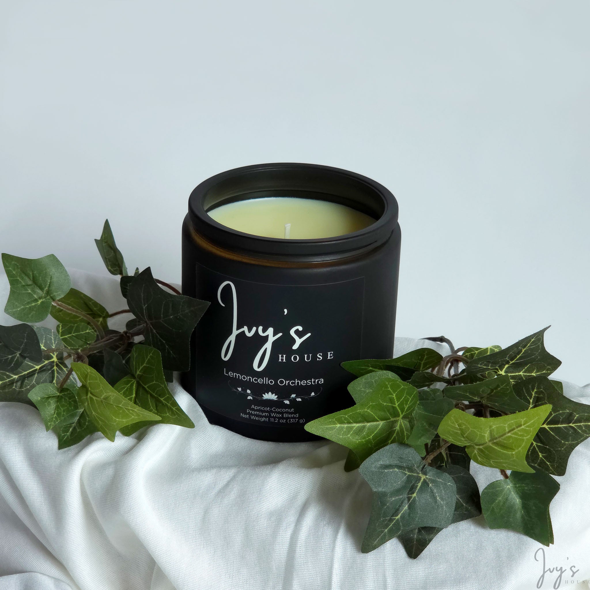 Lemoncello Orchestra premium scented candle by Ivy’s House with ivy leaves on soft white fabric