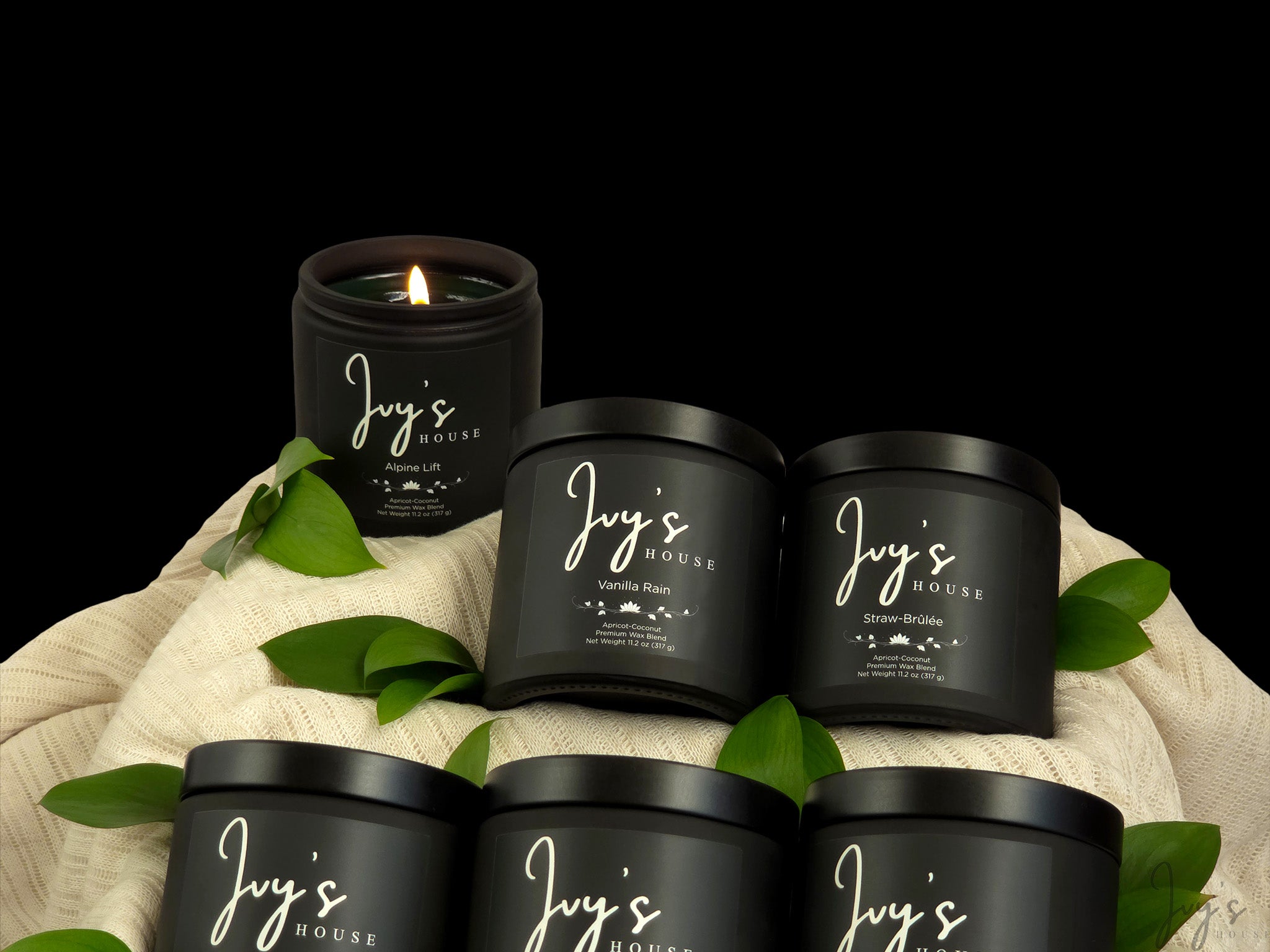 Ivy’s House candle collection featuring multiple scents arranged together on soft fabric with greenery