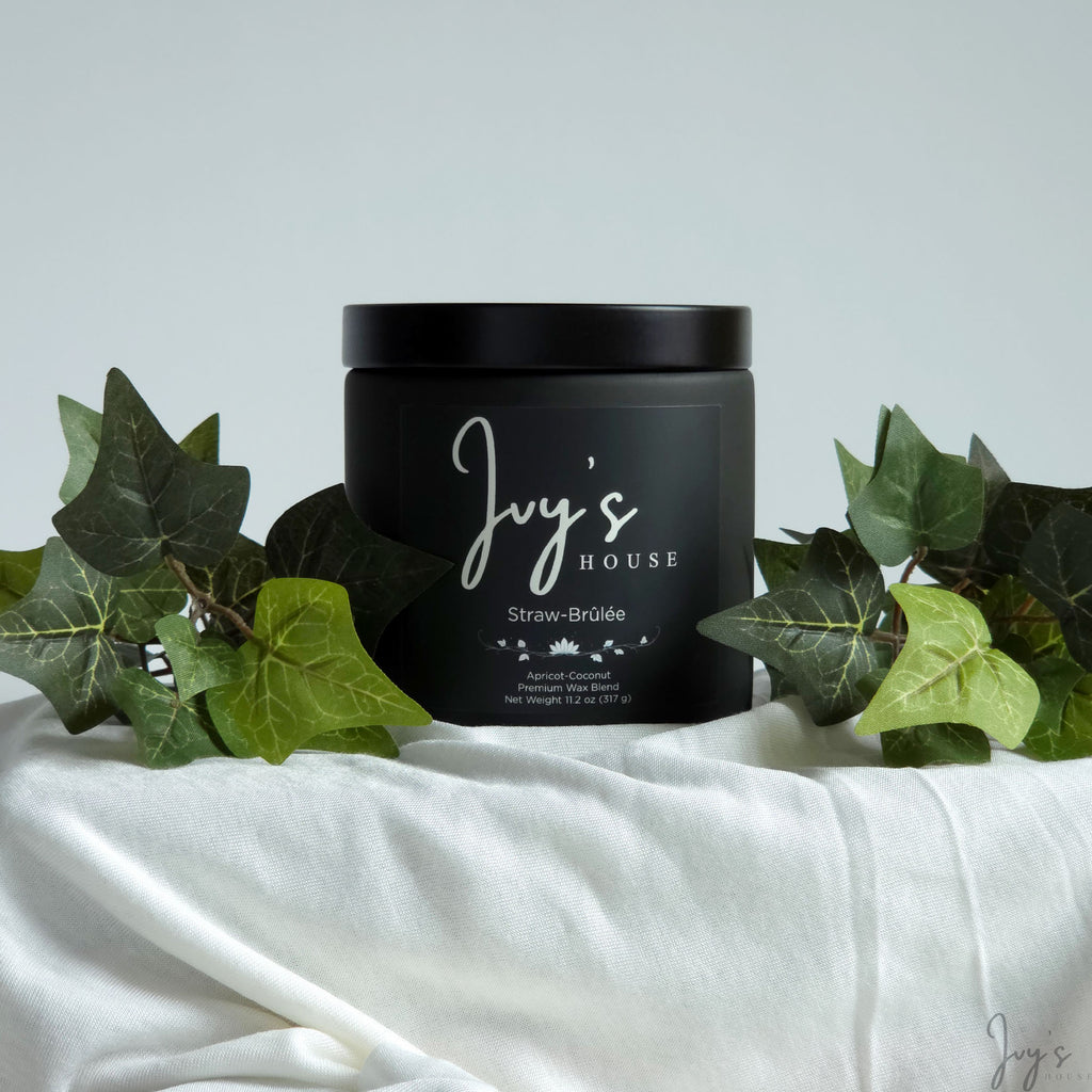Straw-Brûlée premium scented candle by Ivy’s House with ivy leaves on soft white fabric