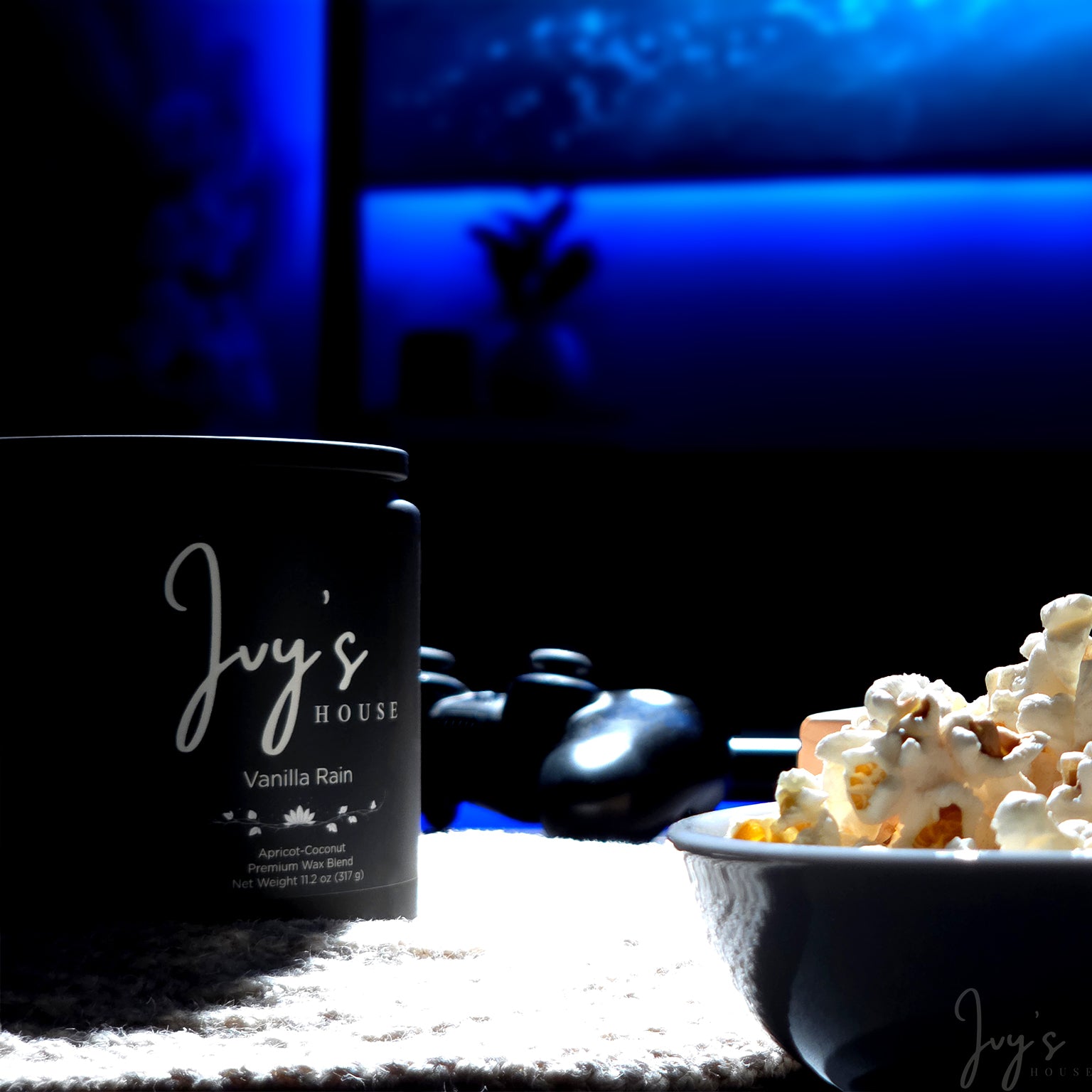 Vanilla Rain candle by Ivy’s House beside popcorn and game controller in a dark, cozy setting