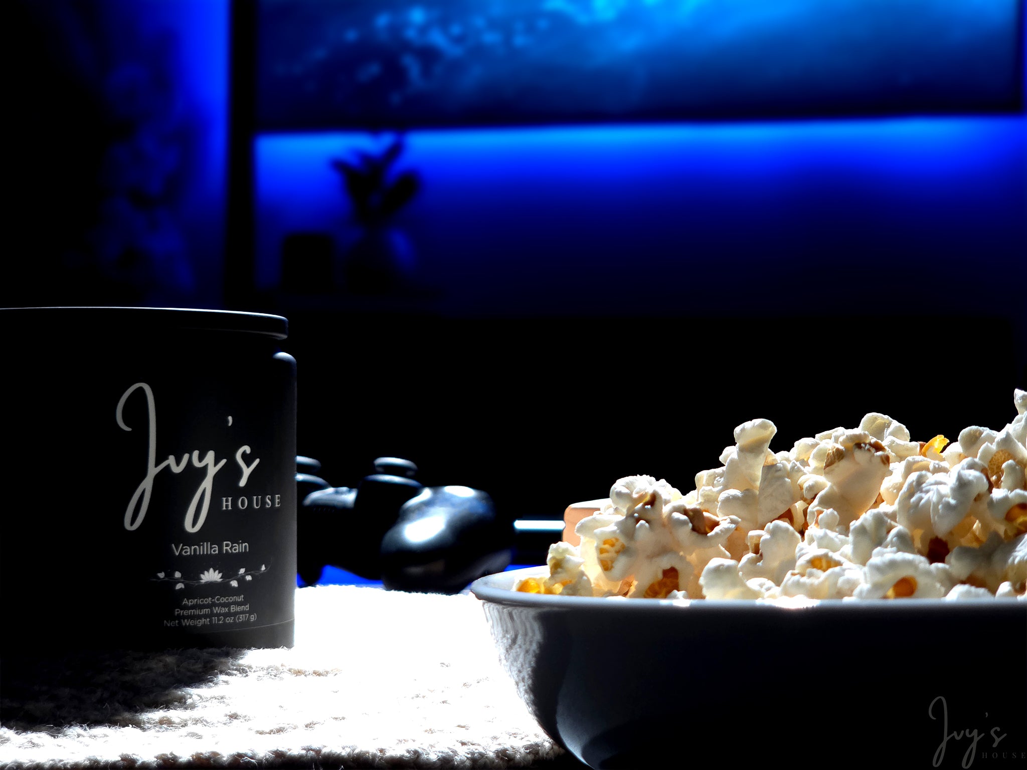 Vanilla Rain candle by Ivy’s House beside popcorn and game controller in a dark, cozy setting