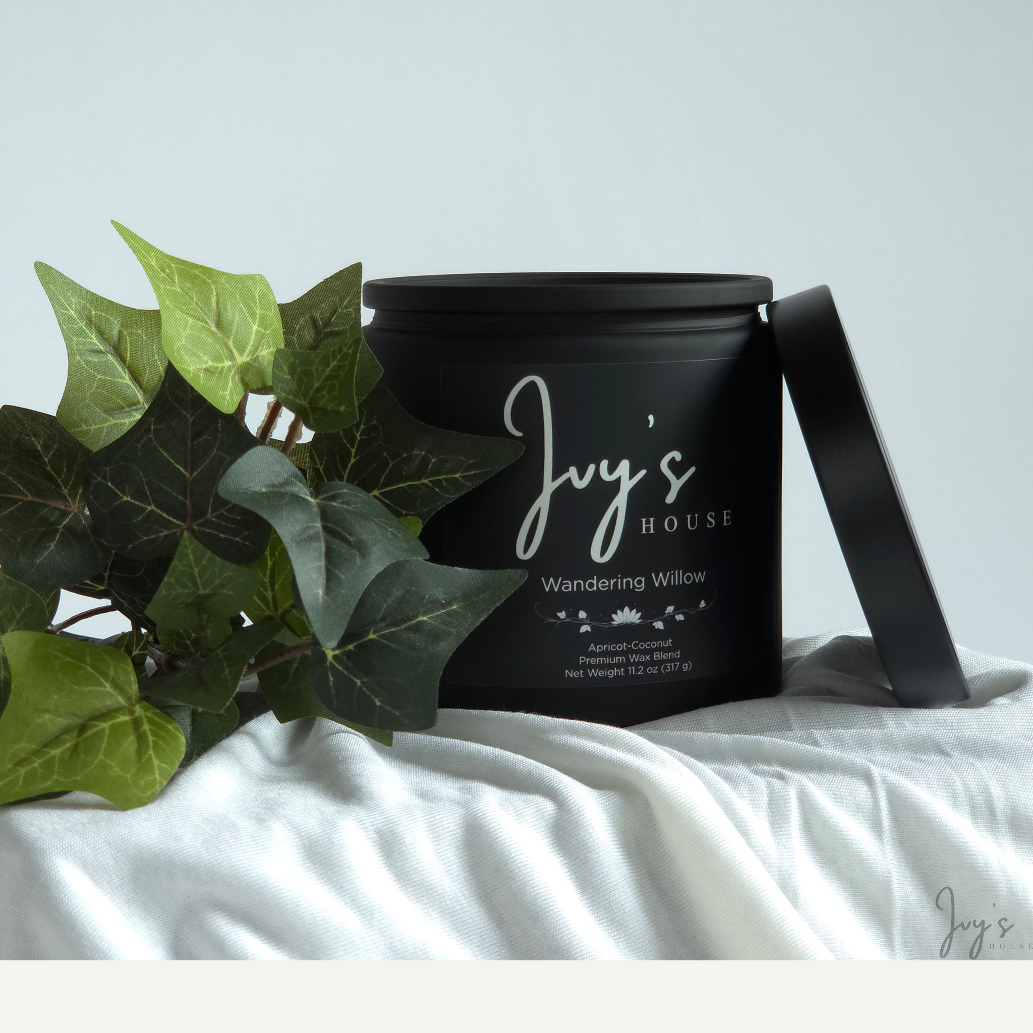 Wandering Willow premium scented candle by Ivy’s House with ivy leaves on soft white fabric