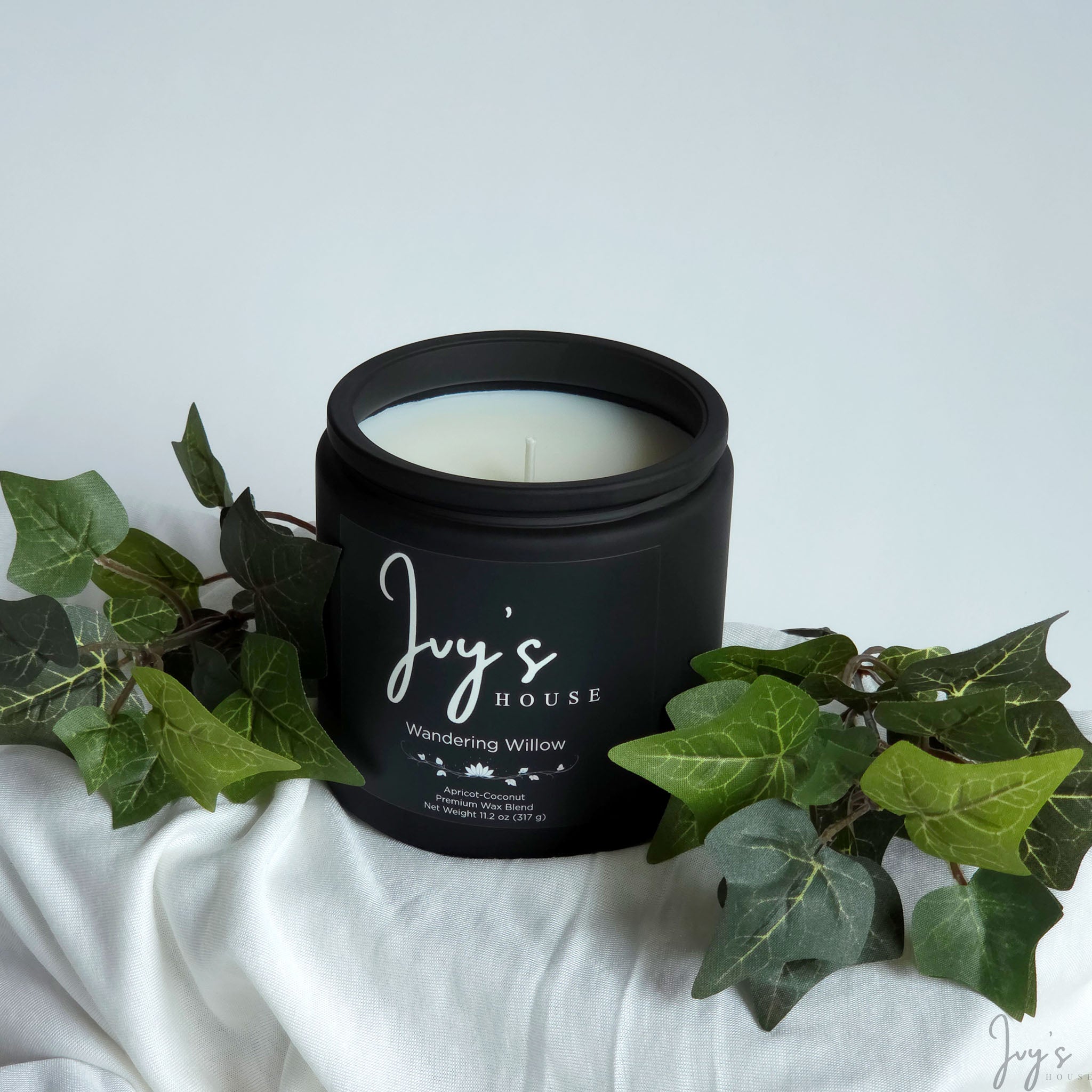 Wandering Willow premium scented candle by Ivy’s House with ivy leaves on soft white fabric
