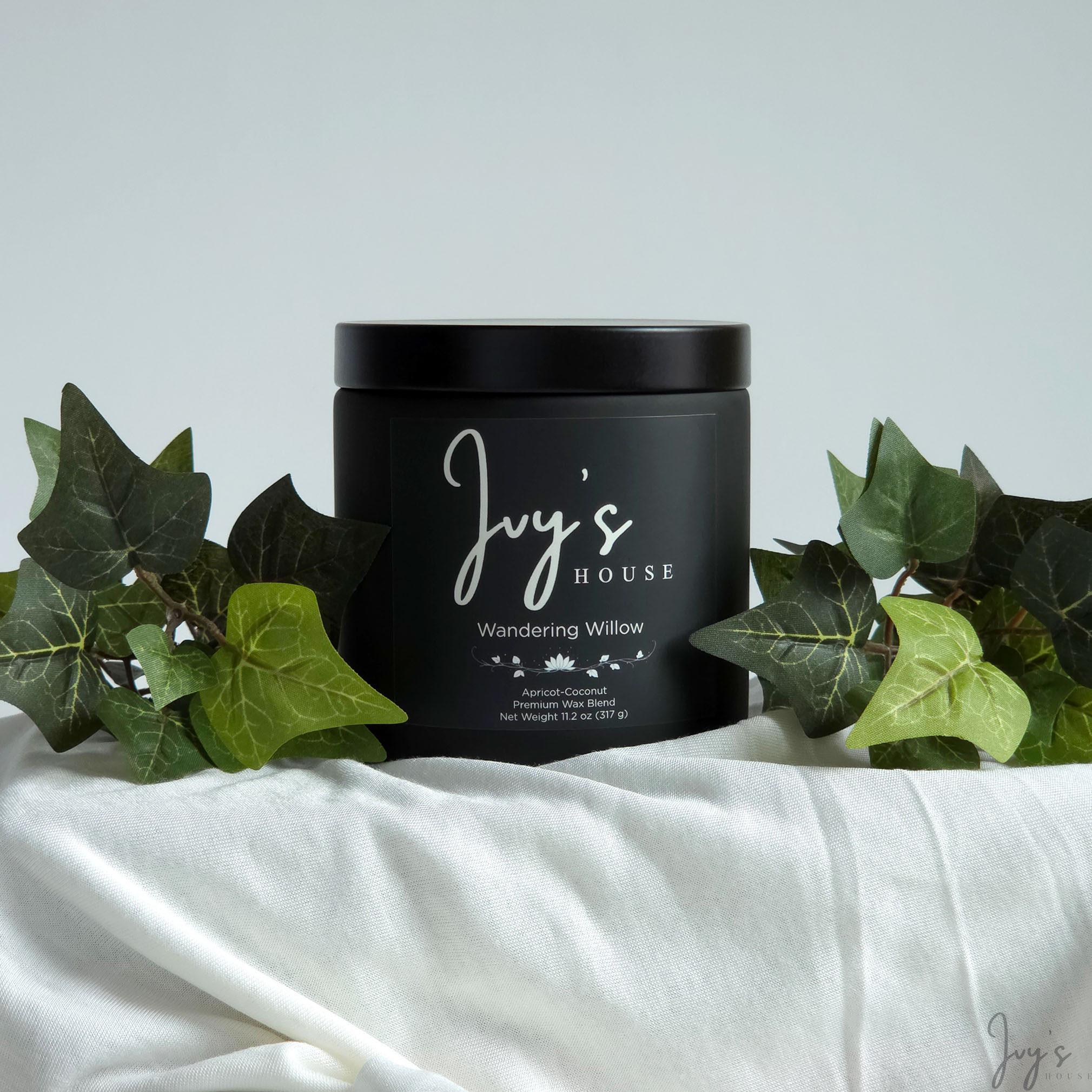 Wandering Willow premium scented candle by Ivy’s House with ivy leaves on soft white fabric