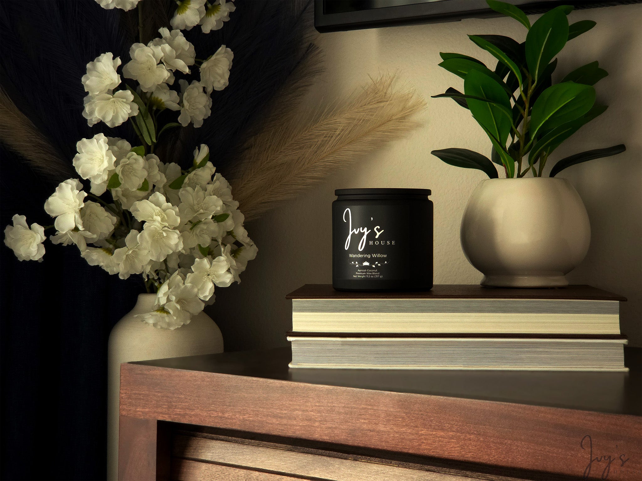 Warm, styled home scene with Ivy’s House Wandering Willow candle, books, and floral decor