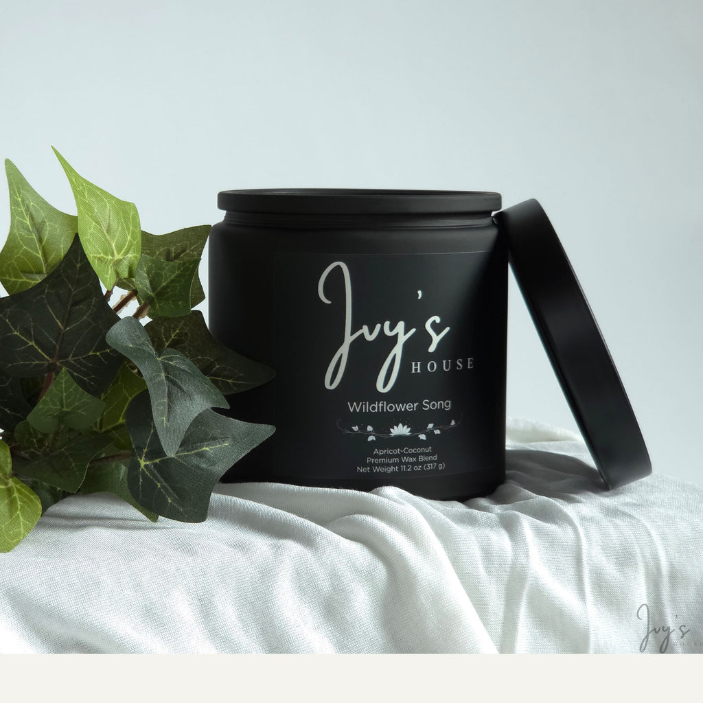 Wildflower Song premium scented candle by Ivy’s House with ivy leaves on soft white fabric