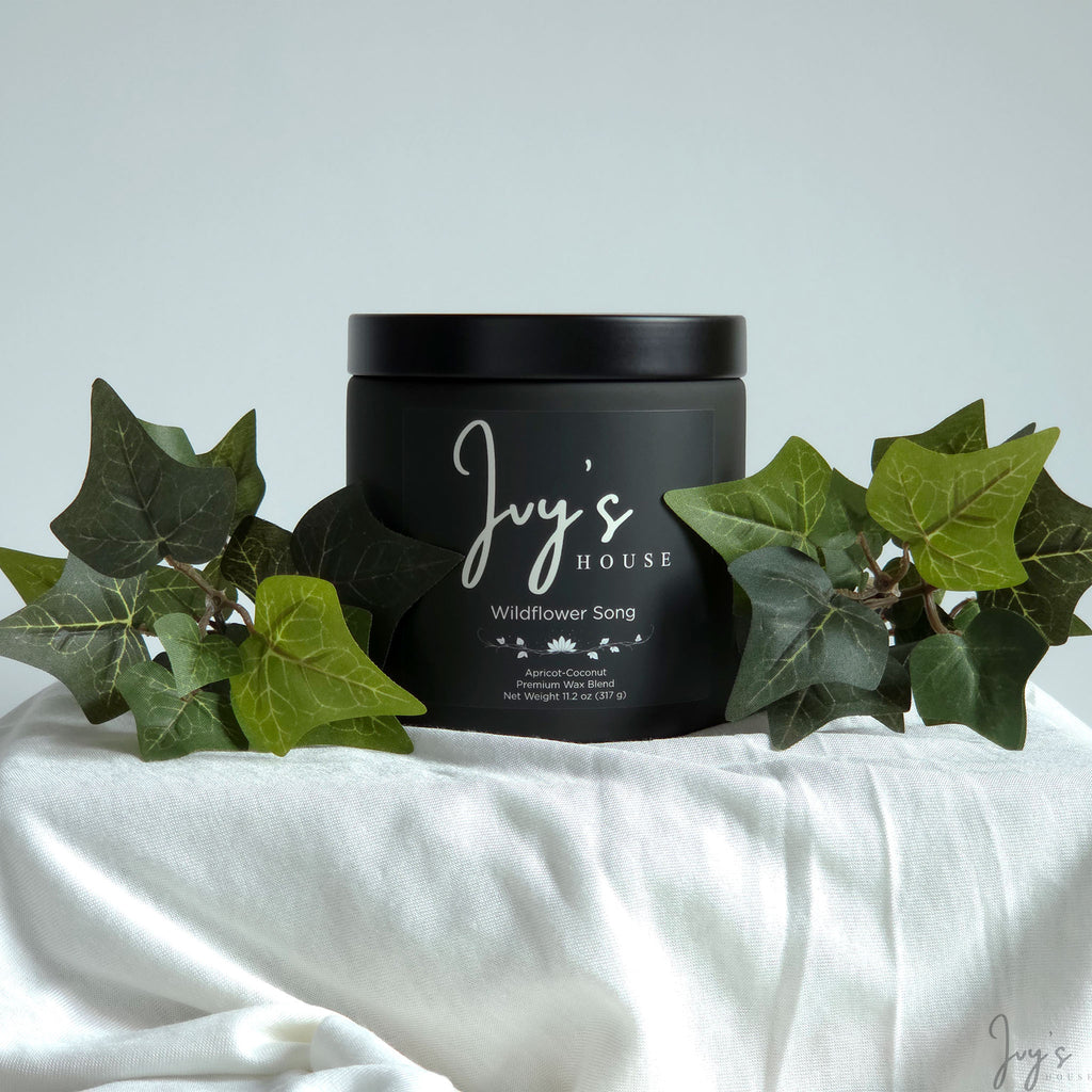 Wildflower Song premium scented candle by Ivy’s House with ivy leaves on soft white fabric