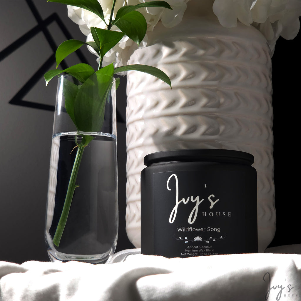 Wildflower Song candle by Ivy’s House beside glass vase and textured ceramic in soft natural light