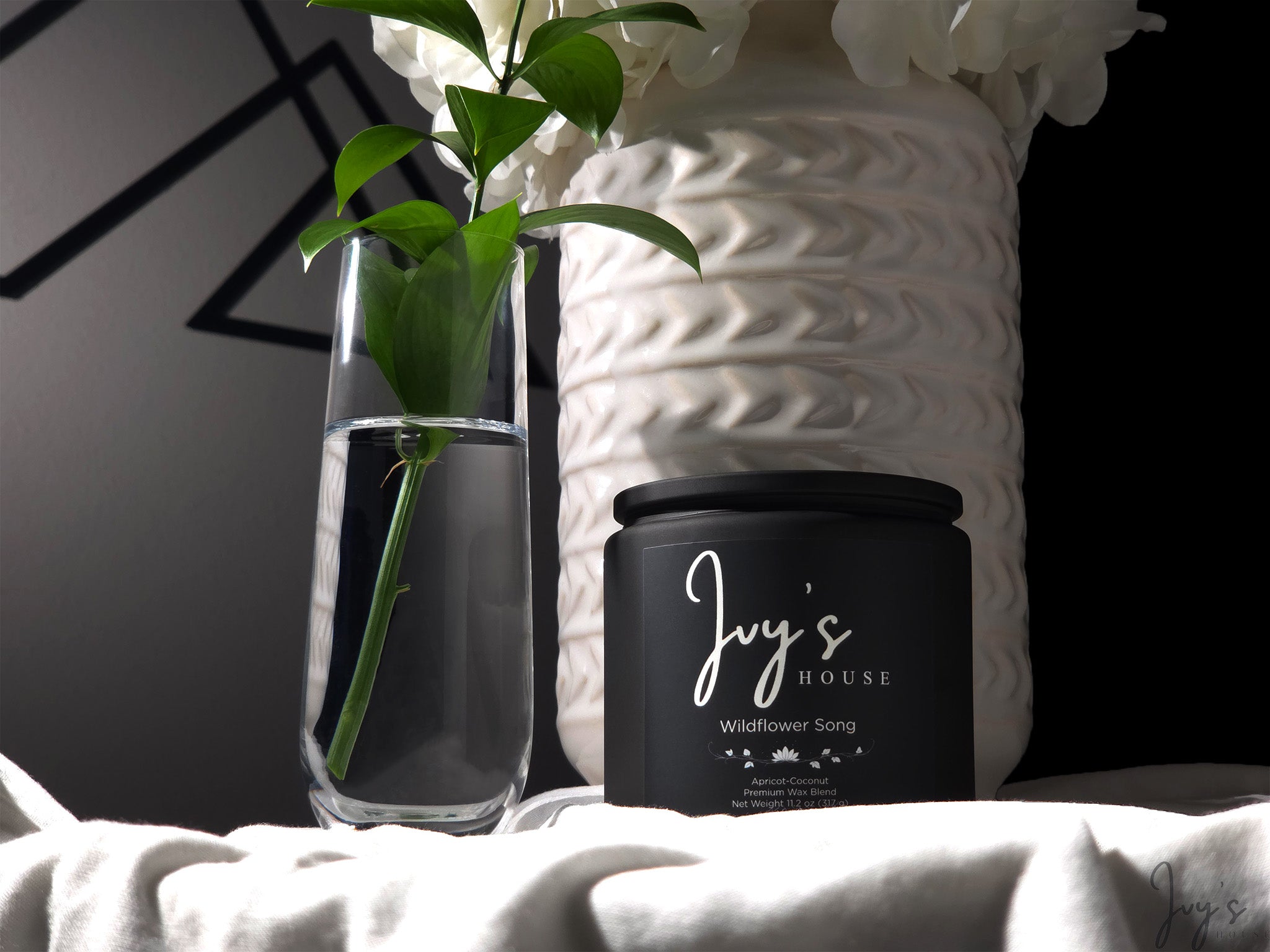 Wildflower Song candle by Ivy’s House beside glass vase and textured ceramic in soft natural light